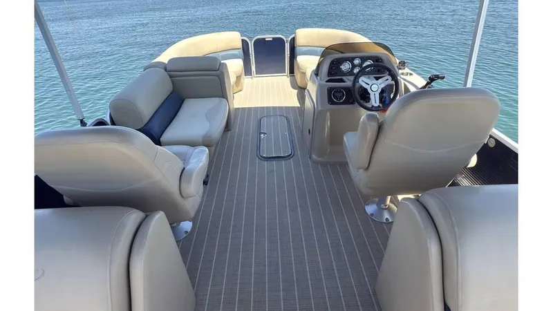 Slide: The Image of 2019 Manitou 23 Aurora LE Bar pontoon boat interior with beige seating and steering console. - 18