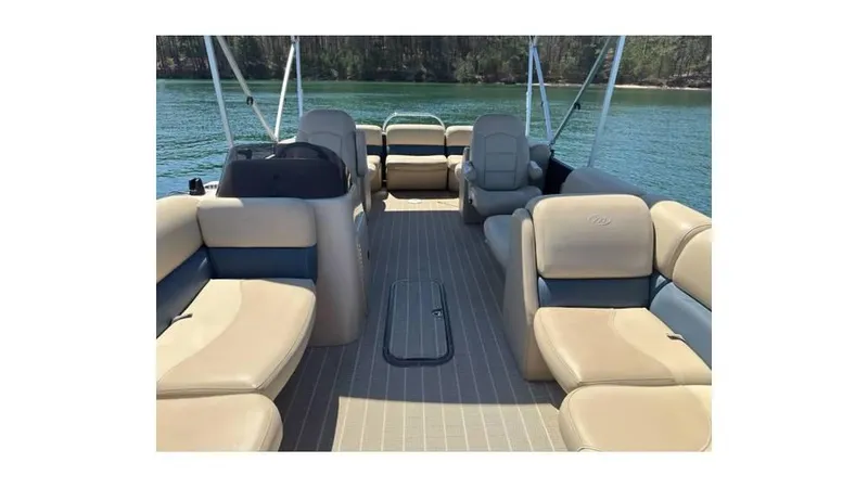 Slide: The Image of 2019 Manitou 23 Aurora LE Bar pontoon boat interior with beige seating on a lake. - 5