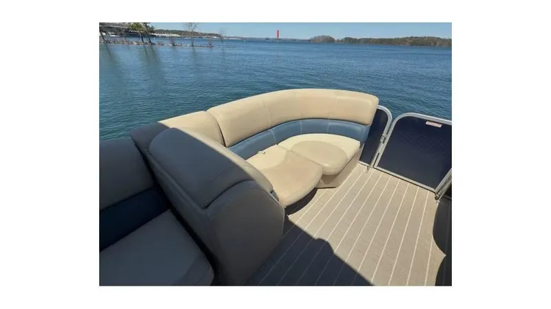 Slide: The Image of 2019 Manitou 23 Aurora LE Bar pontoon boat interior with beige seating on a lake. - 9