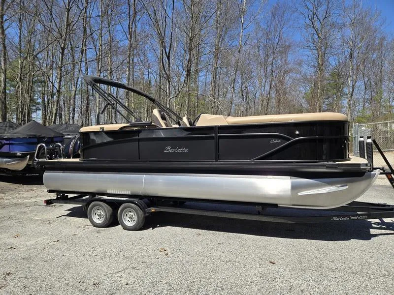 Slide: The Image of 2025 Barletta C22QC pontoon boat on trailer, parked outdoors. - 2