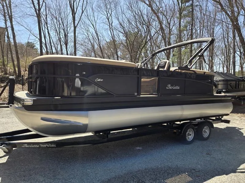 Slide: The Image of 2025 Barletta C22QC pontoon boat on trailer, parked outdoors. - 3