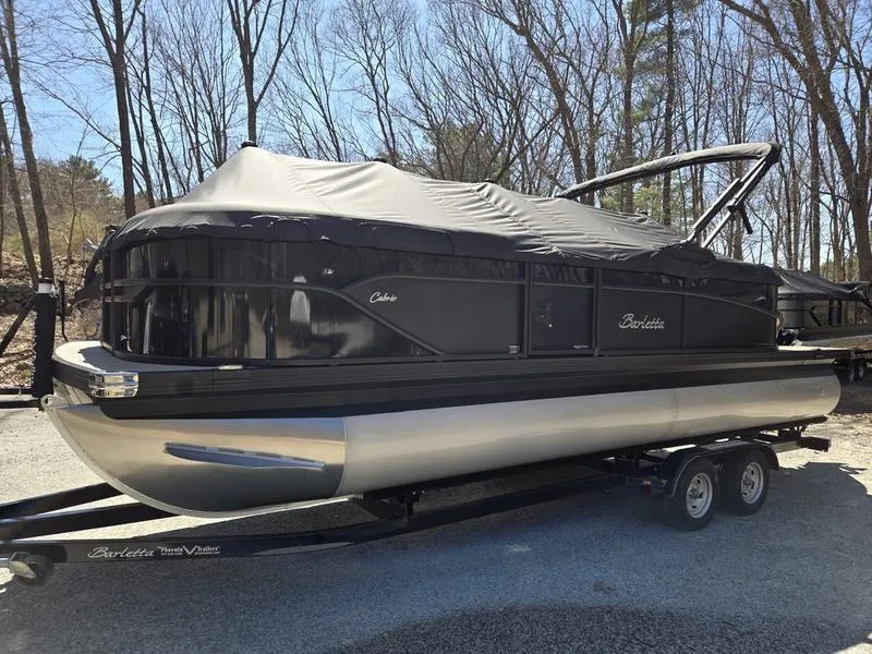 Slide: The Image of 2025 Barletta C22QC pontoon boat with cover on trailer, parked outdoors. - 7
