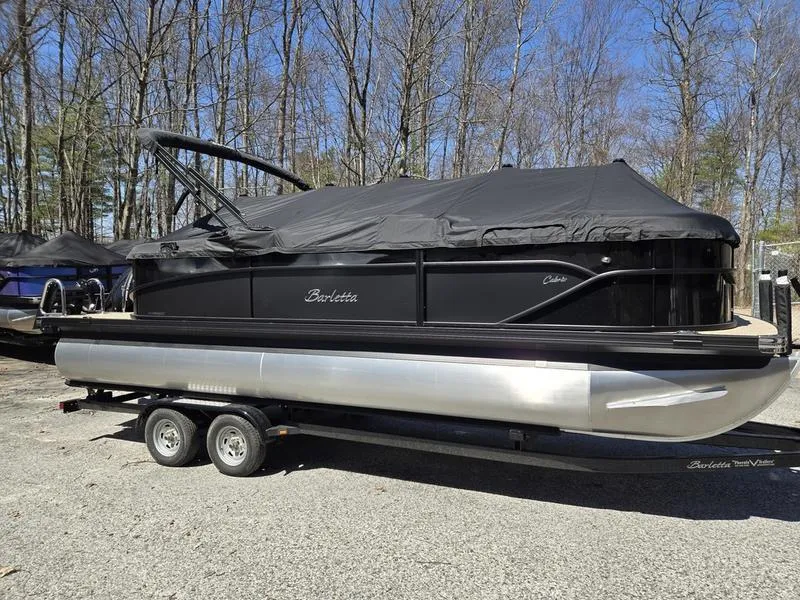 Slide: The Image of 2025 Barletta C22QC pontoon boat with cover on trailer, parked outdoors. - 8