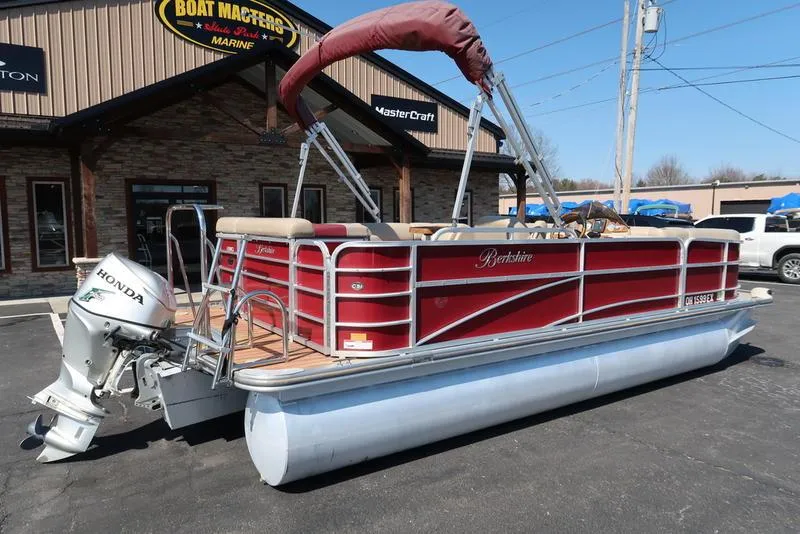 Slide: The Image of 2012 Berkshire G210CL pontoon boat with Honda outboard motor, parked outside a marine shop. - 10