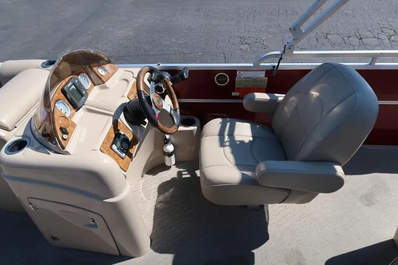 Slide: The Image of Captain's seat and console of 2012 Berkshire G210CL boat, featuring beige upholstery and wood accents. - 20