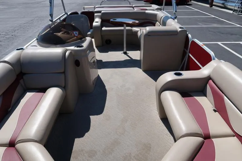 Slide: The Image of 2012 Berkshire G210CL pontoon boat interior with beige and red seating, table, and steering console. - 27