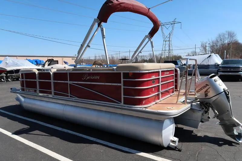 Slide: The Image of 2012 Berkshire G210CL pontoon boat with red exterior and Honda outboard motor in parking lot. - 8