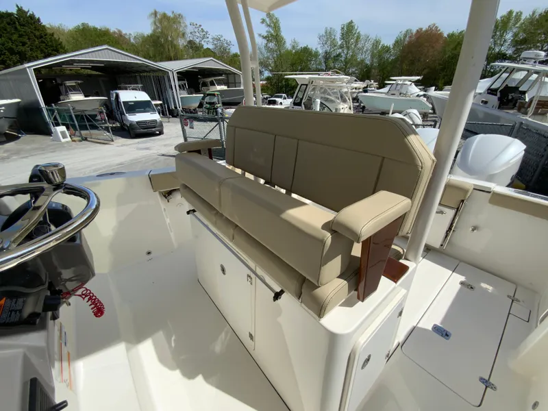 Slide: The Image of 2020 Pursuit S 288 Sport boat interior with beige seating and steering wheel, docked near other boats. - 18