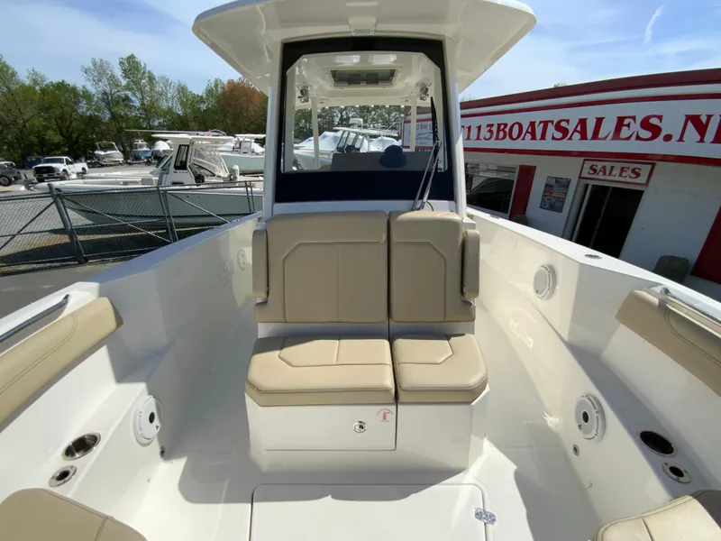 Slide: The Image of 2020 Pursuit S 288 Sport boat interior with beige seating, docked near a boat sales shop. - 24