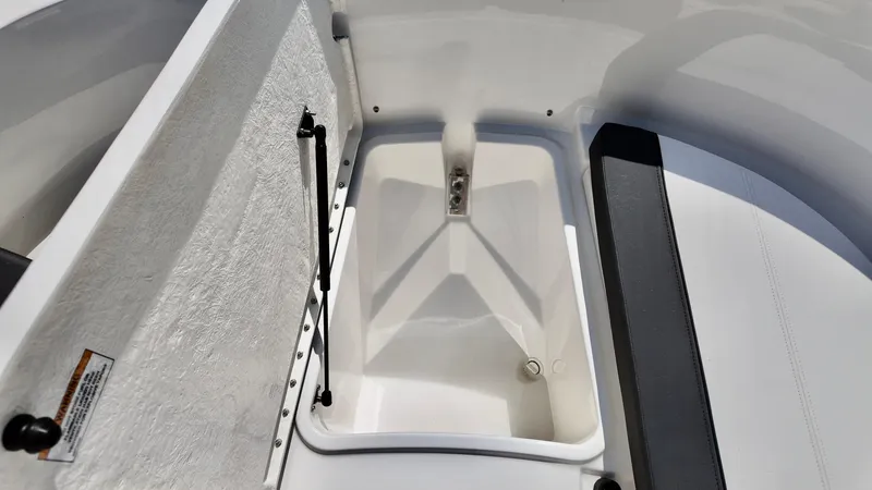 Slide: The Image of 2025 Bayliner Trophy 20 boat storage compartment, open lid, white interior. - 12