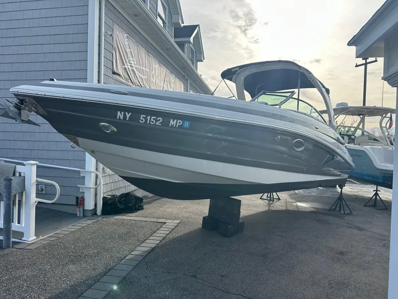 Slide: The Image of 2019 Crownline 290 XSS boat displayed on a stand at a marina. - 0