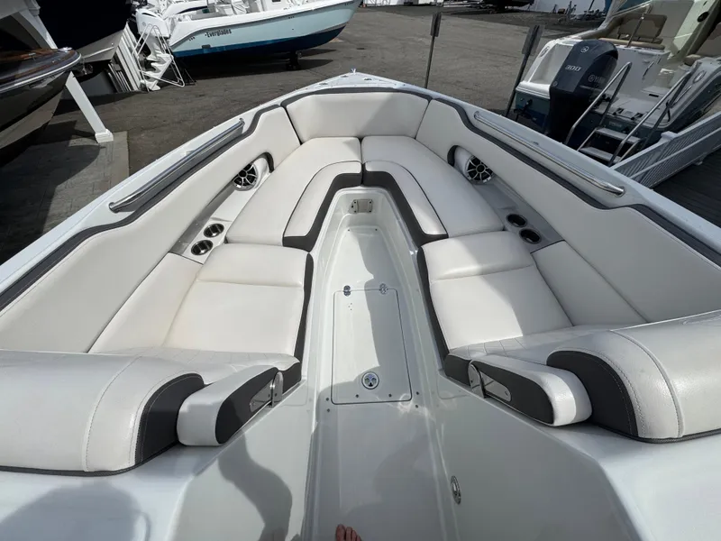 Slide: The Image of 2019 Crownline 290 XSS boat interior with white cushioned seating and cup holders. - 2