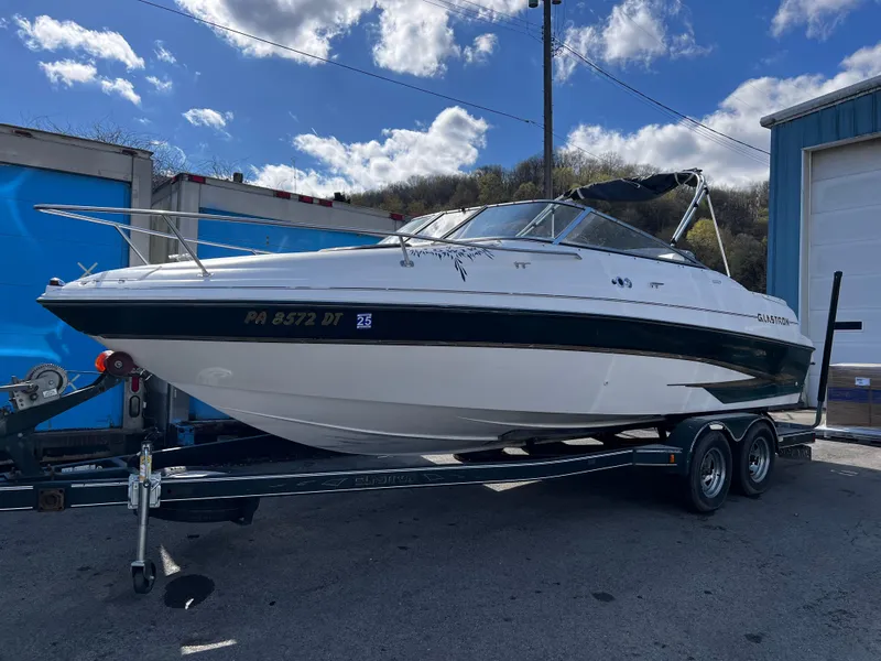 Slide: The Image of 2001 Glastron GS 229 boat on trailer, parked outdoors under a partly cloudy sky. - 0