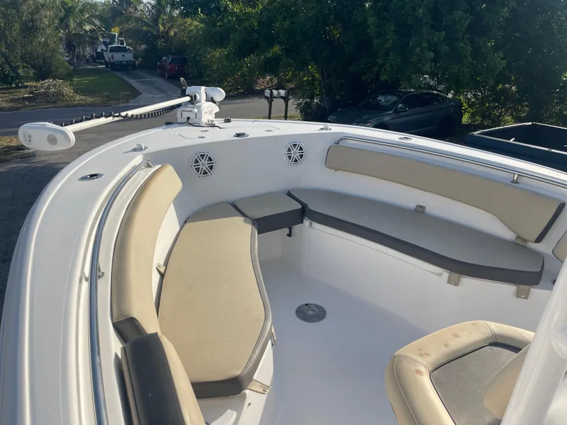 Slide: The Image of 2022 Tidewater Adventure boat interior with cushioned seating and speakers, parked outdoors. - 17