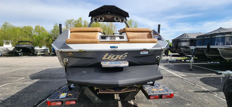 Slide: The Image of 2025 Tigé Ultre ZX boat rear view in a parking lot with other boats. - 5