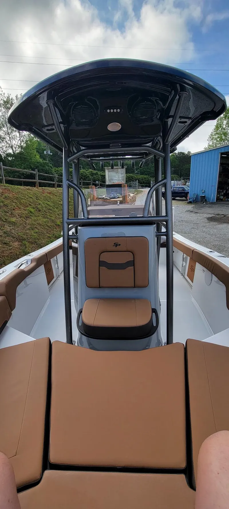 Slide: The Image of 2025 Sea Pro 225 Sandbar boat interior with tan seating and T-top under a cloudy sky. - 17