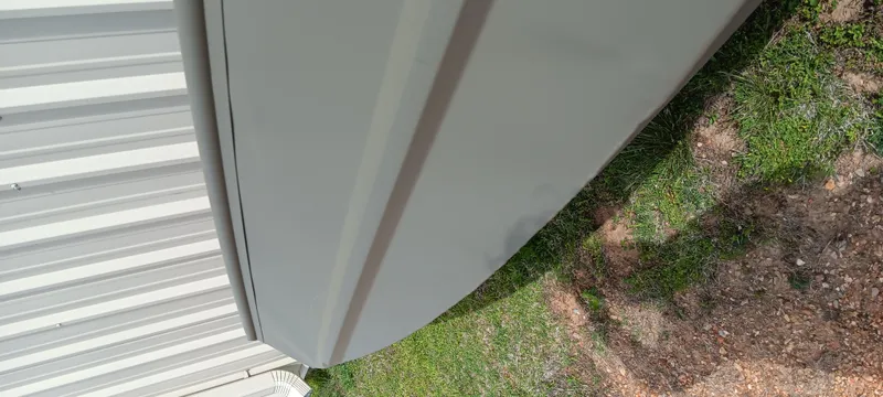 Slide: The Image of 2024 Tracker Grizzly 1036 Jon boat, side view, near metal building and grass. - 10