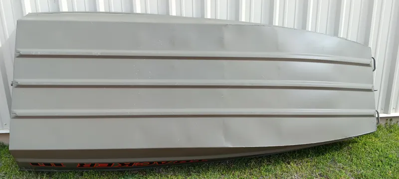 Slide: The Image of 2024 Tracker Grizzly 1036 Jon boat, upside down, on grass near a white wall. - 13