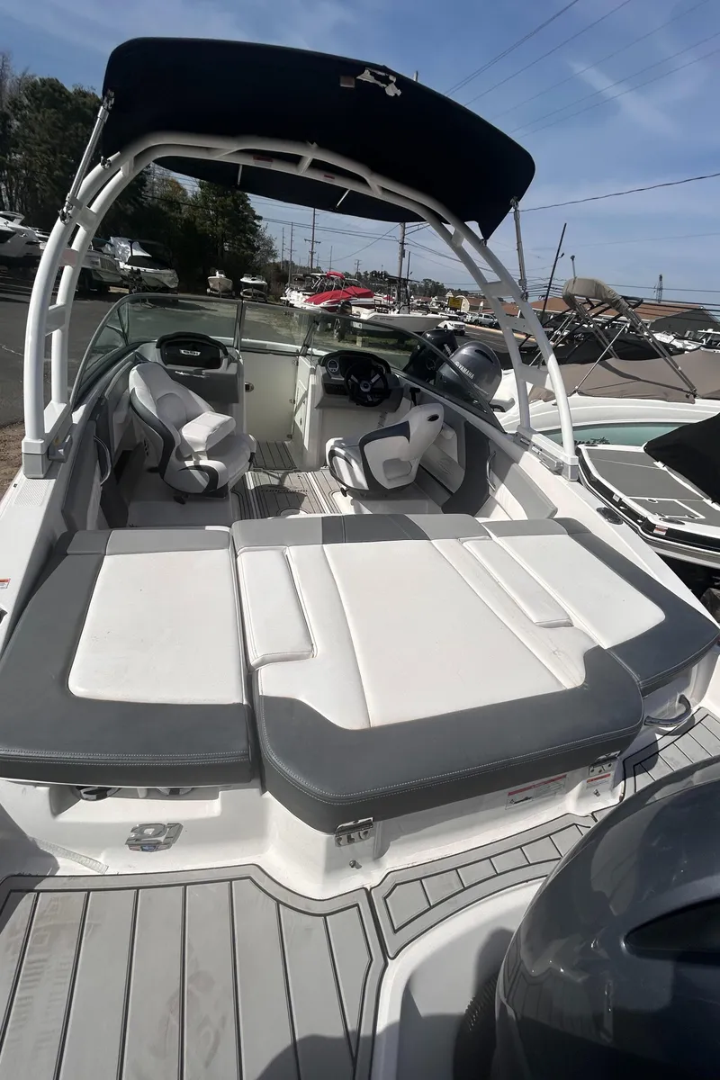 Slide: The Image of 2021 Chaparral SSI boat with sleek seating and canopy, docked under clear skies. - 3