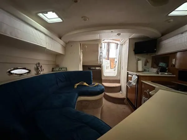 Slide: The Image of Interior of 2002 Bayliner 3055 Ciera with blue seating, kitchenette, and stairs to deck. - 13