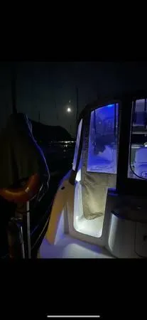 Slide: The Image of 2002 Bayliner 3055 Ciera at night with illuminated interior and moonlit background. - 23