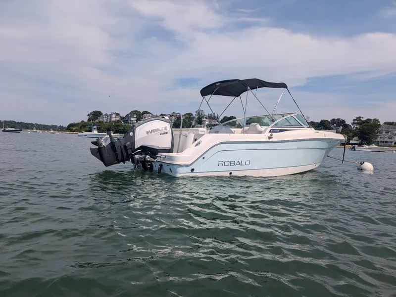 Slide: The Image of 2016 Robalo R227 Dual Console boat on calm water with Evinrude outboard motor. - 2