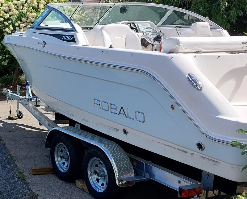 Slide: The Image of 2016 Robalo R227 Dual Console boat on trailer, white exterior, parked outdoors. - 3