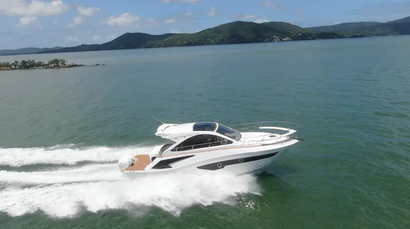 Slide: The Image of 2023 Evolve 400HT yacht cruising on open water with scenic mountain backdrop. - 1