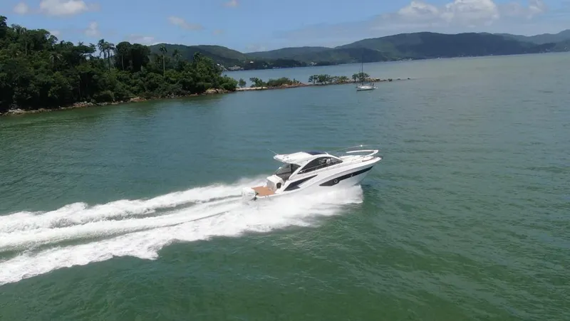 Slide: The Image of 2023 Evolve 400HT yacht cruising on a scenic lake with lush green hills. - 16