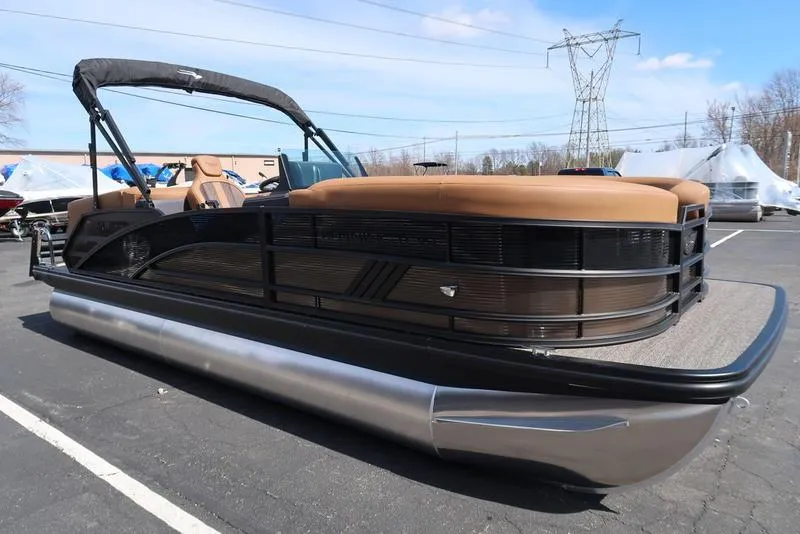 Slide: The Image of 2025 Bennington M Quad Bench 22 MFB pontoon boat with tan seating, parked outdoors. - 12