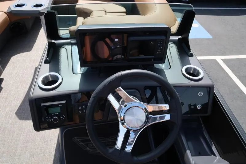 Slide: The Image of Steering console of 2025 Bennington M Quad Bench 22 MFB with modern controls and cup holders. - 32