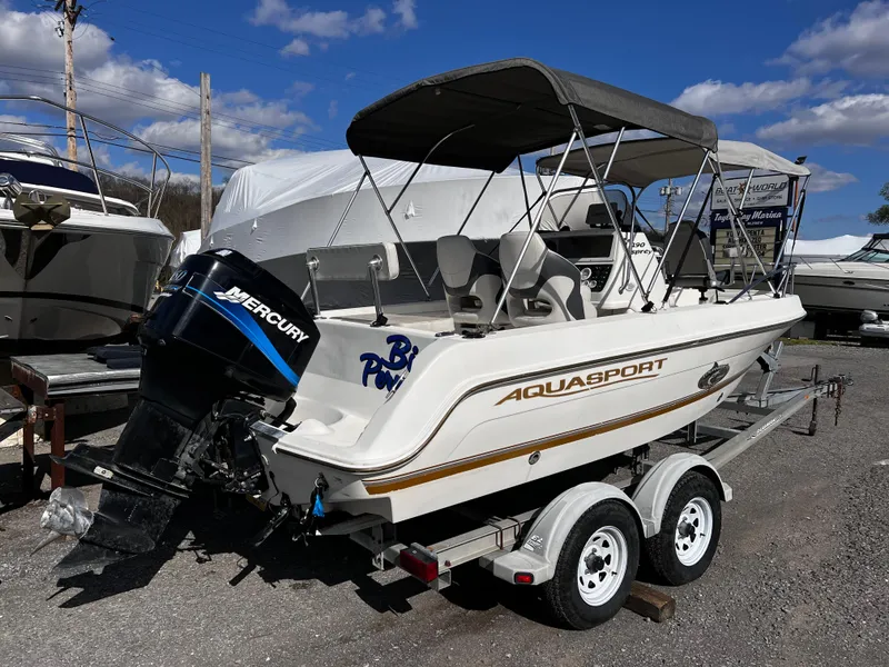Slide: The Image of 2001 Aquasport 190 Osprey boat on trailer with Mercury outboard motor, parked outdoors. - 2