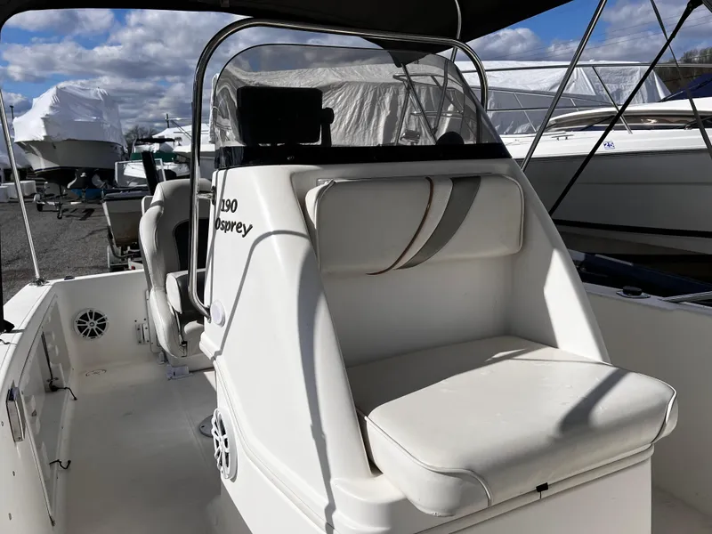 Slide: The Image of 2001 Aquasport 190 Osprey boat interior with seating and console, docked under blue sky. - 8