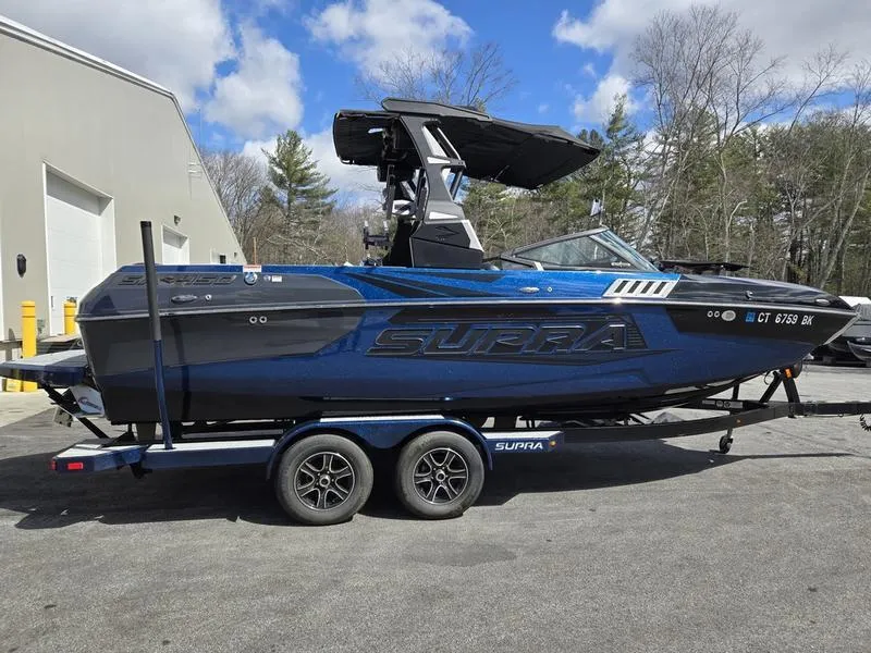 Slide: The Image of 2019 Supra SA boat on trailer, parked outdoors under a partly cloudy sky. - 1