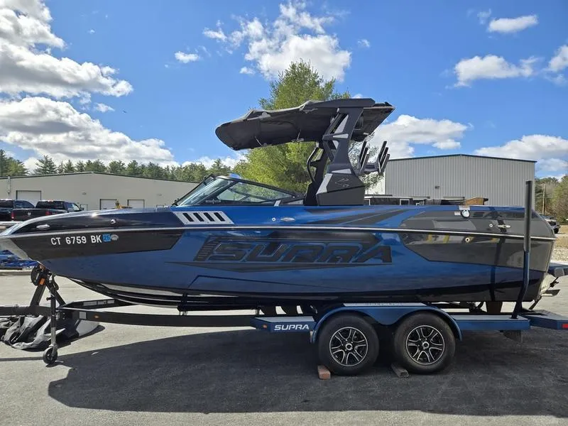 Slide: The Image of 2019 Supra SA boat on trailer, blue and black design, parked outdoors under a cloudy sky. - 3