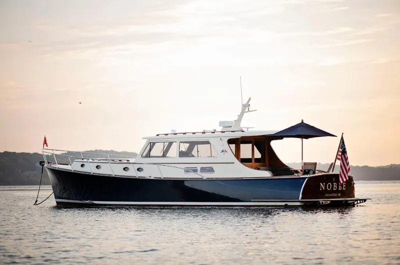 The Image of 2003 Vicem 51 Classic yacht on calm water at sunset, featuring elegant design and American flag. - 0