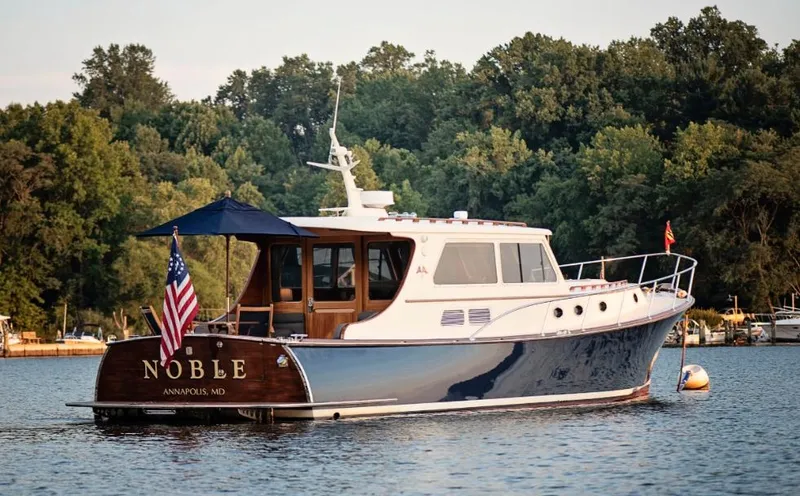 Slide: The Image of 2003 Vicem 51 Classic yacht on serene water, surrounded by lush trees. - 2
