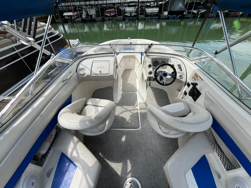 Slide: The Image of 2006 Larson Senza 206 boat interior with white and blue seating, docked at marina. - 16