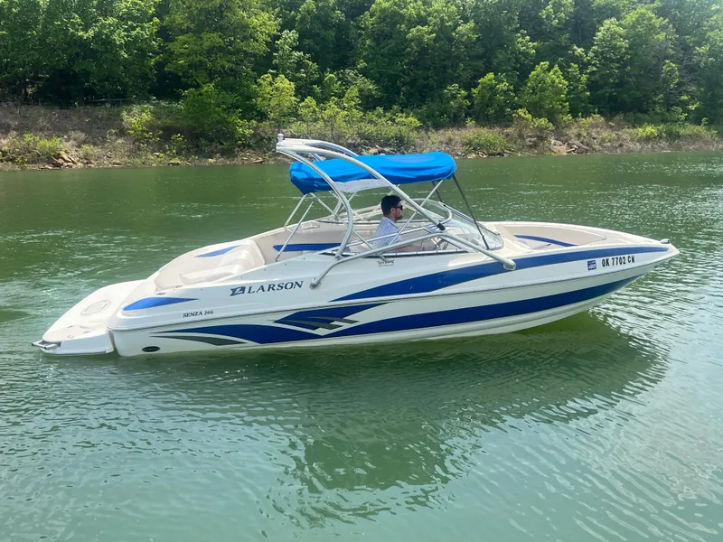 Slide: The Image of 2006 Larson Senza 206 boat with blue canopy on a calm lake. - 4