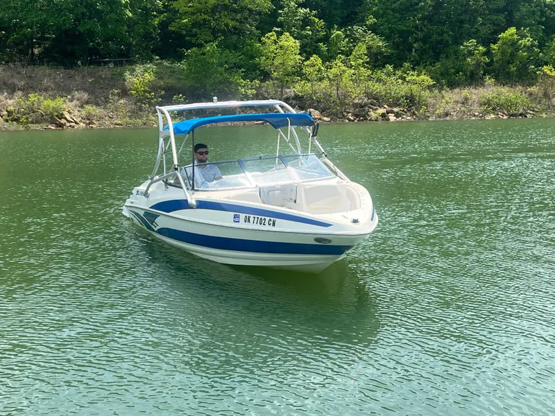 Slide: The Image of 2006 Larson Senza 206 boat on a calm lake with lush green surroundings. - 5