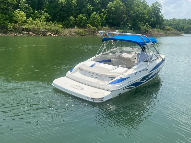 Slide: The Image of 2006 Larson Senza 206 boat with blue canopy on a serene lake. - 7