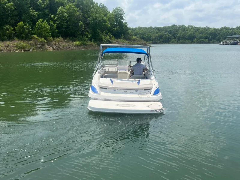 Slide: The Image of 2006 Larson Senza 206 boat cruising on a serene lake with lush green surroundings. - 8