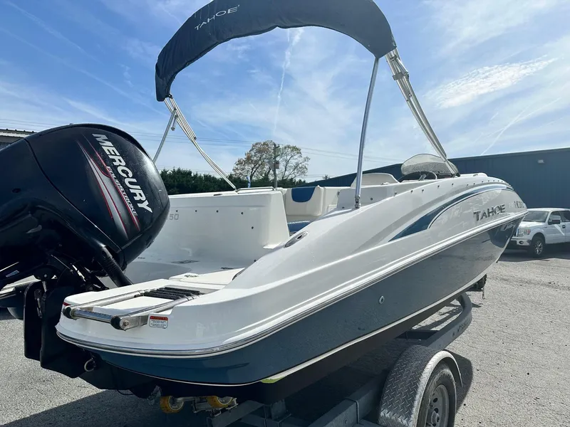 Slide: The Image of 2016 Tahoe 2150 Deck Boat on trailer with Mercury outboard motor, under clear blue sky. - 3