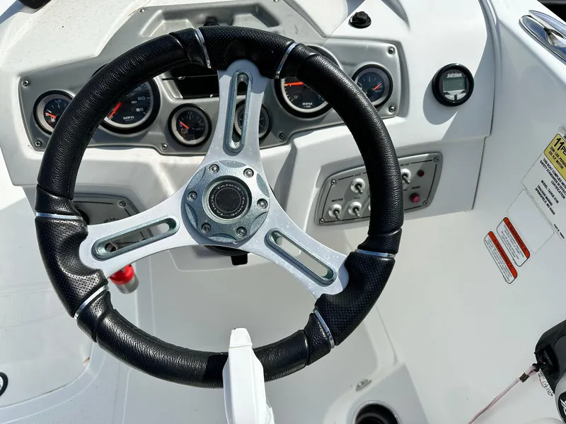 Slide: The Image of Steering wheel and dashboard of 2016 Tahoe 2150 Deck Boat, featuring gauges and controls. - 7