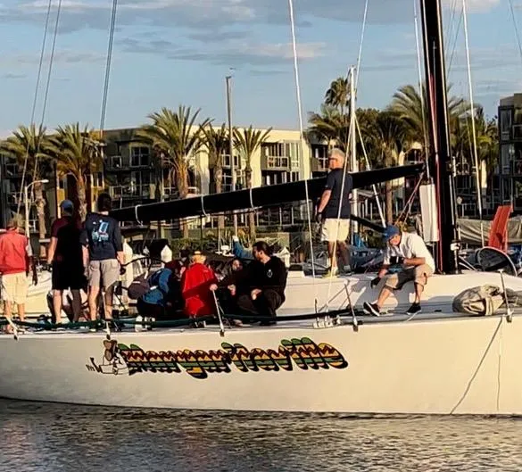 Slide: The Image of A group of people on a 1989 Custom Modified SLP 52 sailboat, docked near palm trees. - 28