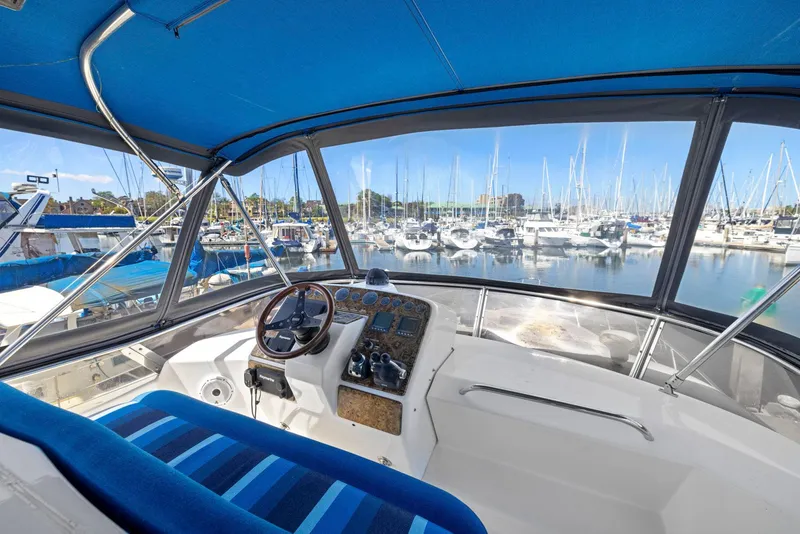 Slide: The Image of 2008 Dyna 51 yacht helm with marina view, featuring blue canopy and striped seating. - 18