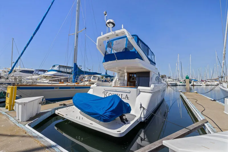 Slide: The Image of 2008 Dyna 51 yacht docked at marina, featuring blue canopy and covered equipment. - 2