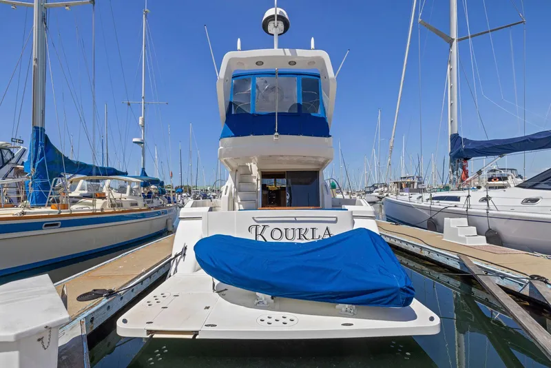 Slide: The Image of 2008 Dyna 51 yacht docked at marina, covered in blue tarp, surrounded by sailboats. - 3