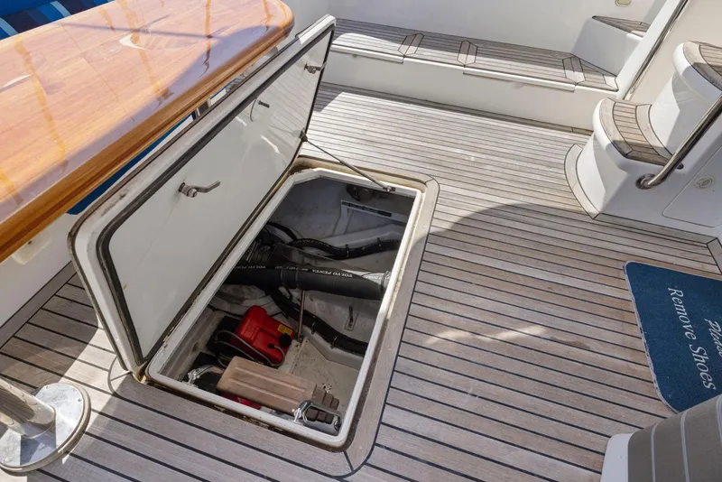 Slide: The Image of 2008 Dyna 51 yacht deck with open storage compartment, wooden table, and seating area. - 45