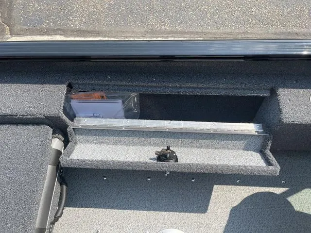 Slide: The Image of 2025 Lund 1775 Adventure Sport boat storage compartment with gray interior and visible documents. - 11